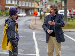 Pointe-Claire mayoral candidate Tim Thomas, right, speaks with resident Peter Campbell while campaigning on Monday.