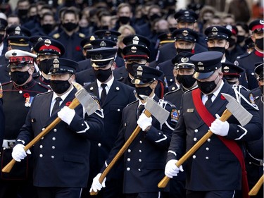 Members of the Toronto Fire Department carry ceremonial axes as they take part in the funeral service for fallen firefighter Pierre Lacroix in Montreal on Friday, Oct. 29, 2021.