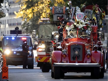 An antique ladder truck carrying flowers and wreaths makes its way to Notre-Dame Basilica during the funeral service for fallen firefighter Pierre Lacroix in Montreal on Friday, Oct. 29, 2021.