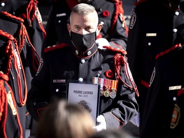 The Montreal Fire Department honour guard prepares to load the urn into a car outside Notre-Dame Basilica during the funeral service for Pierre Lacroix in Montreal on Friday, Oct. 29, 2021.