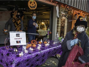 Bev Hall and Don Jackson use a hockey stick and a basket to hand out candy to trick-or-treaters in Montreal West during Halloween last year.