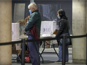 Leisa Lee, right, arrives to cast her ballot at an advance poll for next week's municipal elections at the Concordia University building on Ste-Catherine St. on Sunday, Oct. 31, 2021.