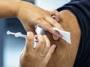 A vaccinator administers a dose of COVID-19 vaccine in Montreal.