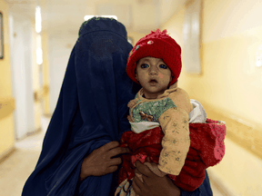A woman carries a baby in the malnutrition ward at a Kabul hospital, Oct. 23, 2021. More than half of Afghanistan's population is short of food.