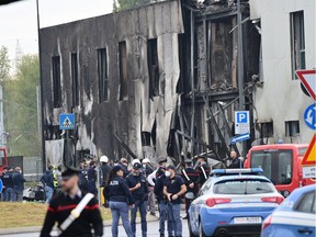 Police and rescue teams stand outside an apparently vacant office building where a small plane crashed in the Milan suburb of San Donato on Oct. 3, 2021.