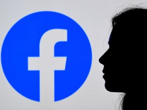 In this file photo illustration, a person looks at a smart phone with a Facebook App logo displayed on the background, on Aug. 17, 2021, in Arlington, Va. The whistleblower who shared a trove of Facebook documents alleging the social media giant knew its products were fuelling hate and harming children's mental health revealed her identity on Sunday, Oct. 3, 2021, in a televised interview, and accused the company of choosing "profit over safety."
