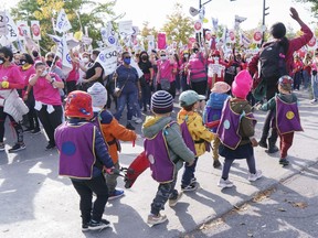 Children from a daycare walk past a demonstration of daycare workers on the first day of rotating strikes in Montreal Oct. 12, 2021.
