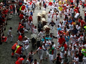 Runners sprint in front of Torrestrella fighting bulls at the entrance to the bull ring during the first running of the bulls of the San Fermin festival in Pamplona on July 7, 2014.