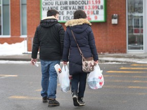 Shoppers carry plastic grocery bags full of groceries.