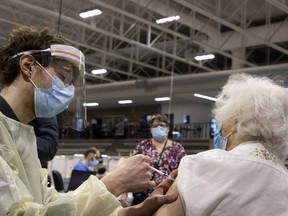 A health-care worker gives a COVID-19 vaccine to Marion Locke at the Bill Durnan Arena in March. If teams from health authorities don't visit private seniors’ residences (RPAs), "the third-dose coverage is going to be rather low, because RPA residents who require care will not be travelling to vaccination centres,” said Regroupement québécois des résidences pour aînés president Marc Fortin.