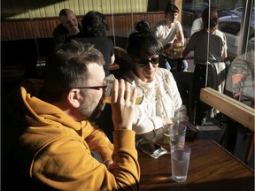 Patrons Omer Moussaly, left, and Aida Vosoughi enjoy a beer and the last rays of the sun at Vices & Versa bar in Little Italy Monday Nov. 1, 2021.