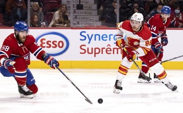 Montreal Canadiens defenseman David Savard knocks the puck away as Calgary Flames left wing Andrew Mangiapane looks on during 2nd-period NHL action in Montreal on Thursday, Nov. 11, 2021.