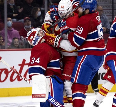 Montreal Canadiens defenseman David Savard (58) pulls Calgary Flames centre Sean Monahan (23) away from Montreal Canadiens goaltender Jake Allen (34) after Monahan collided with Allen after the play, during 2nd-period NHL action in Montreal on Thursday, Nov. 11, 2021.