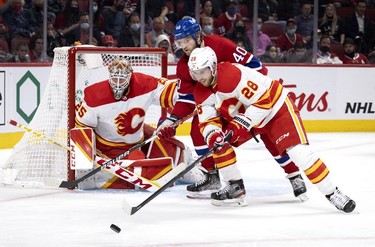 Calgary Flames centre Elias Lindholm (28) and Montreal Canadiens right wing Joel Armia (40) reach for the puck as Calgary Flames goaltender Jacob Markstrom (25) looks on during 3rd-period NHL action in Montreal, on Thursday, Nov. 11, 2021.