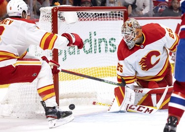 Calgary Flames goaltender Jacob Markstrom (25) looks back to see Montreal Canadiens centre Nick Suzuki's (14) score as Calgary Flames defenseman Christopher Tanev (8) tries to cover the net, during 3rd-period NHL action in Montreal, on Thursday, Nov. 11, 2021.