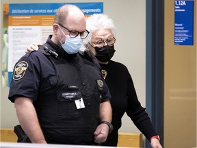 Cora Tsouflidou walks beside a court police officer to hide from the media as she arrives at the Laval courthouse on Wednesday, November 24, 2021.
