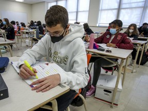Masked students work at their desks during French class at John F. Kennedy High School in Montreal in 2020. As of Nov. 15, 2021, they can go maskless in class.