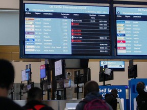 Travellers walk near an electronic flight notice board displaying cancelled flights at OR Tambo International Airport in Johannesburg on Nov. 27, 2021.