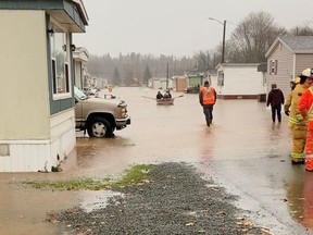 Emergency services workers help people leave as residents row a boat across a flooded area in Antigonish, Nova Scotia, Nov. 23, 2021 in this still image taken from social media video.