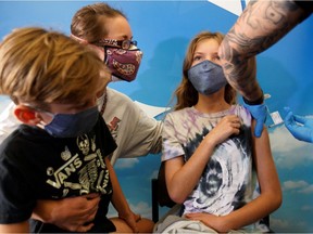 Madeleine Strickland, 11, receives the Pfizer-BioNTech coronavirus vaccine as her mother Monica and brother Liam, 6, look on at Rady's Children's hospital vaccination clinic in San Diego, California, U.S., November 3, 2021.