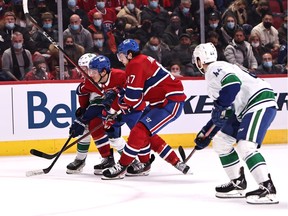 Vancouver Canucks defenceman Quinn Hughes (43) battles for the puck against Montreal Canadiens centre Jake Evans (71) and right wing Josh Anderson (17) during game at the Bell Centre on Nov. 30, 2021.