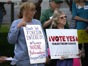 Protesters hold signs encouraging a yes vote, with one sign saying "Don't let foreign interests influence Maine referendums!"