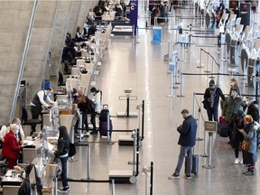Travellers wait to check in for their American Airlines flight departing from Trudeau airport last month. The measures implemented over the past 20 months range from requiring all users to wear masks on site to increasing the frequency of maintenance and disinfection in the terminal building.