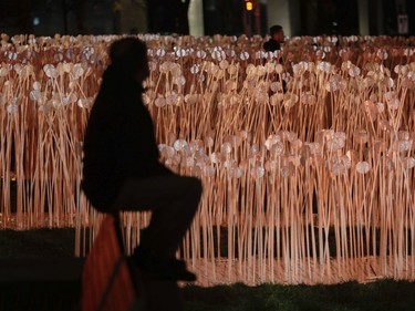 A man walks through a "field" of rods, part of an installation that is called Entre les Rangs, at the 12th edition of Luminothérapie, a luminous art walk in Quartier des Spectacles.