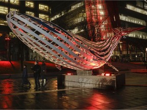 Johanne Raynault and Adrien Rousseau walk under an installation called Echoes: A Voice From Uncharted Waters at the 12th edition of Luminothérapie at the Quartier des Spectacles.