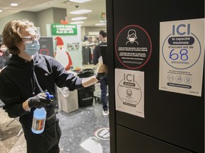 A clerk washes walls in front of signs that indicate the total number of clients allowed in a store at the Complexe Desjardins on Friday, December 4, 2020.