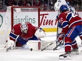 Montreal Canadiens goaltender Jake Allen prepares to cover the puck as right-winger Cole Caufield keeps Tampa Bay Lightning left-winger Ross Colton at bay during second period in Montreal on Dec. 7, 2021.