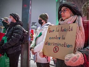 A woman holds a sign during protest rally against Bill 21 outside Place des Arts in Montreal on Wednesday, Dec. 15, 2021.