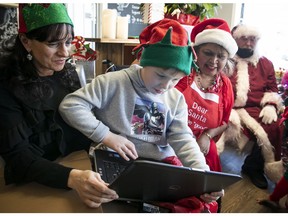 David O’Reilly, 10, gets a look at his new laptop computer that was given to him by Santa and his helpers Sandy Sorrenti, left, the owner of Cafe Luxe MTL in Île-Perrot and Lovie Rivard, the organizer of the toy drive event held on Sunday.