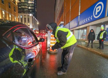 Security guard Jacques David explains to hockey fans that they can't enter the Bell Centre parking lot ahead of the Montreal Canadiens' game against the Philadelphia Flyers in Montreal on Thursday, Dec. 16, 2021 after the Canadiens were asked by Quebec's public health department to hold the game without fans.
