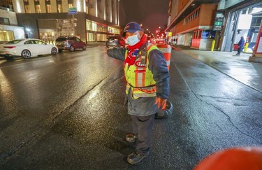 Parking attendant Sam Suos waves cars past the Bell Centre parking lot ahead of the Montreal Canadiens' game against the Philadelphia Flyers in Montreal on Thursday, Dec. 16, 2021 after the Canadiens were asked by Quebec's public health department to hold the game without fans.