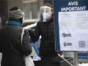 People receive a ticket for a later appointment to get a COVID-19 rapid test kit at a pharmacy on the corner of St-Laurent Blvd. and Mont-Royal Ave. on Monday December 20, 2021.