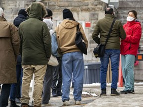 A health-care worker speaks to people lining up for COVID-19 tests at the Hôtel-Dieu site in Montreal Monday December 20, 2021.