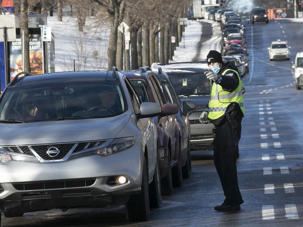  a montreal police officer directs drivers toward the covid testing and vaccination centre at the olympic stadium on dec. 21, 2021.