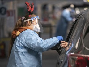 Nurse Krystel Paquette tries to show some holiday spirit as she performs COVID-19 testing at a drive-thru clinic at the Olympic Stadium in Montreal on Dec. 21, 2021.