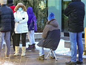 A man brought a camping stool for the long wait for booster vaccinations at the Gerry-Robertson Centre in the Pierrefonds borough of Montreal on Dec. 21, 2021.