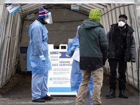 Health-care workers and security staff greet people at a combination vaccination and testing clinic on Centre St. in Montreal on Dec. 22, 2021.
