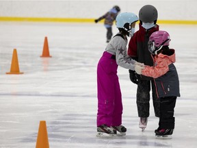 Kids help each other learn to skate during holiday skating hours at the Kirkland Sports Complex in Montreal, on Dec. 19, 2021.
