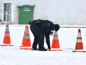 A Montreal police investigator moves evidence markers at the scene of a fatal shooting on Verdier St. In the St-Léonard borough of Montreal Tuesday Dec. 28, 2021. A man was shot there Monday night and was declared dead Tuesday morning.