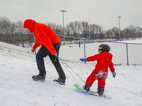 Todd Phillips uses a string to tow his son Gawain back up the tobogganing hill at Parc Le Ber in the Pointe-St.-Charles district of Montreal Tuesday December 28, 2021.