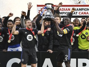 Samuel Piette, de CF Montréal, à gauche, et Victor Wanyama soulèvent la Coupe Voyageurs après avoir battu le Toronto FC 1-0 pour devenir le champion canadien 2021 au Stade Saputo le 21 novembre 2021, à Montréal.