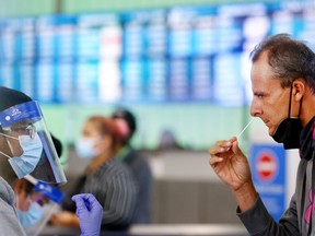 A passenger who arrived from Italy administers a self-collected nasal swab on the first day of a new rapid COVID-19 testing site for arriving international passengers at Los Angeles International Airport (LAX) on December 3, 2021 in Los Angeles, California. The free voluntary tests are being offered to arriving passengers in the Tom Bradley International Terminal by the Los Angeles County Department of Health after the county confirmed its first case of the Omicron variant December 2.