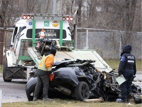 Montreal police and towing crews remove a car that lost control and flipped over the guard railing of the Sources Blvd. overpass landing on Donegani Street in Montreal, on Saturday, December 18, 2021.