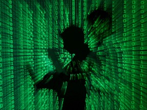 An illustration picture shows a projection of binary code on a man holding a laptop computer, in an office in Warsaw June 24, 2013.