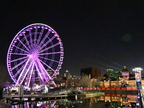 La grande roue de Montréal est vue le 4 avril 2020, dans le quartier touristique du Vieux-Port, et illuminée aux couleurs de l'arc-en-ciel en soutien aux victimes de la pandémie de COVID-19.