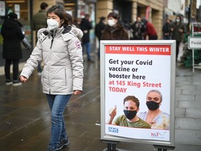 A woman walks past signage outside a pop-up vaccination centre for the Covid-19 vaccine or booster, in Hammersmith and Fulham in Greater London on Friday, Dec. 3, 2021, as rollout accelerates in England.